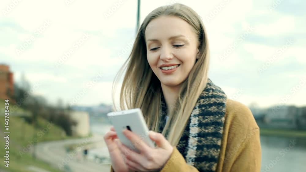 Beautiful girl looks happy while walking on boulevards and browsing internet on smartphone
Beautiful girl looks happy while walking on boulevards and browsing internet on smartphone