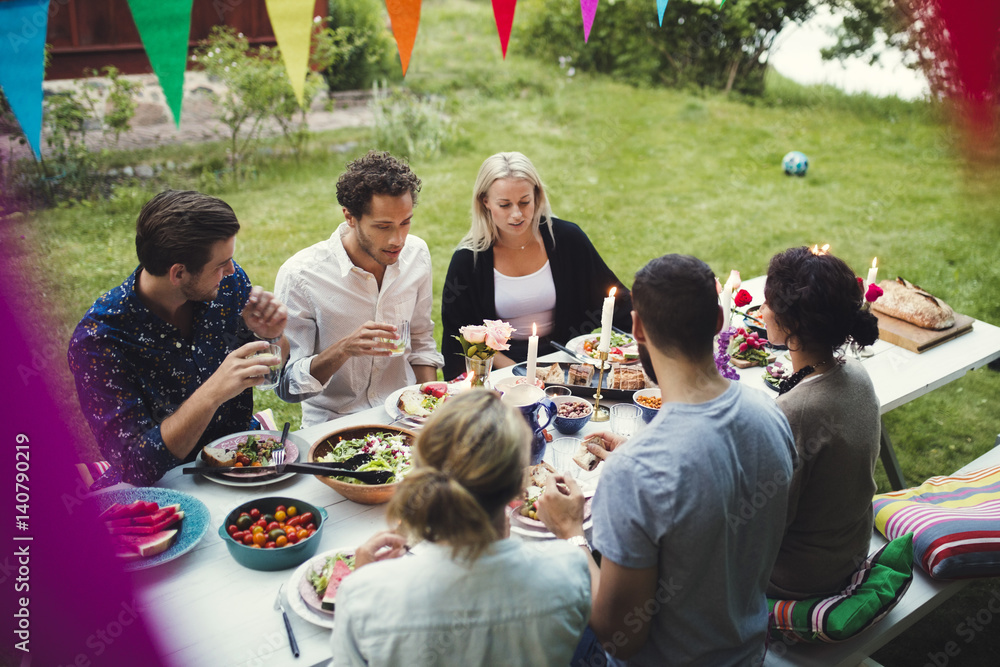 High angle view of friends enjoying dinner at garden party High angle view of friends enjoying dinner at garden party