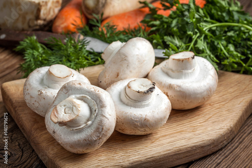 Champignon mushrooms on a wooden cutting board.