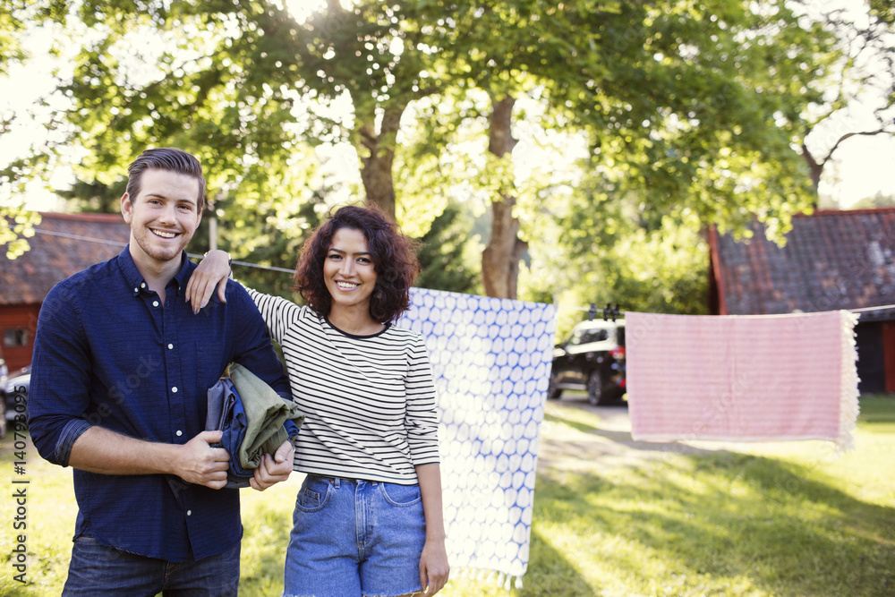 Portrait of smiling friends standing against clothesline in backyard Portrait of smiling friends standing against clothesline in backyard