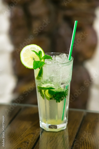 Two fresh mojitos cocktail on wooden background. Mojitos with mint leaves, lime and ice.