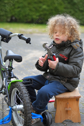 Kleinkind repariert baut bastelt an seinem Fahrrad photo