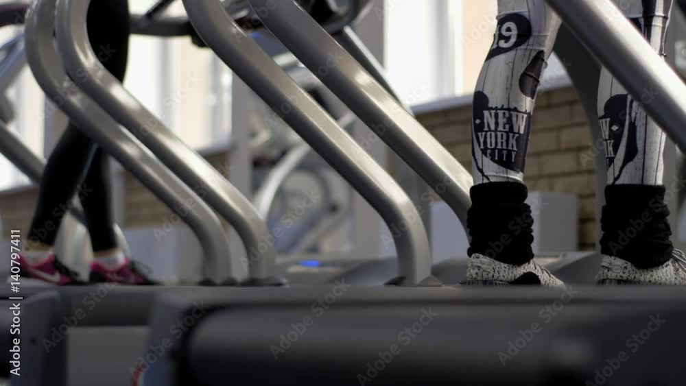 Exercising in the gym, treadmill cardio workout - detail close-up of beautiful legs in slow motion shot. Sculpt, Shape and Define Your Legs Workout. Exercising in the gym, treadmill cardio workout - detail close-up of beautiful legs in slow motion shot. Sculpt, Shape and Define Your Legs Workout.