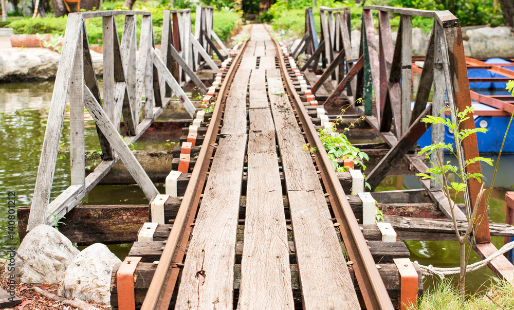 Small railroad tracks made of steel and wood build a bridge over the water canal.