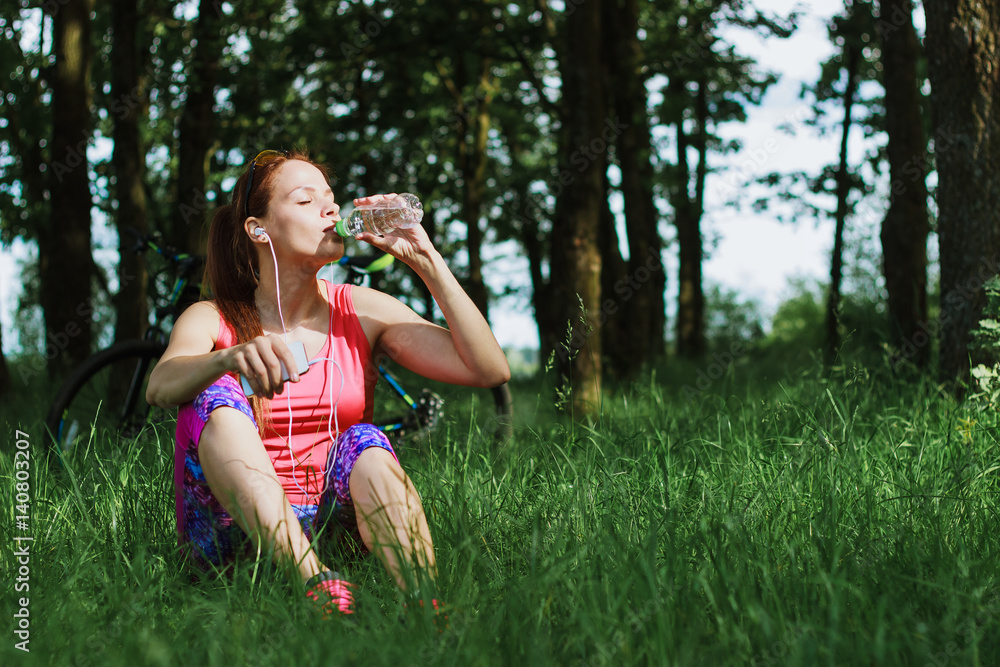 Fototapeta premium Attractive woman drinks water from a bottle