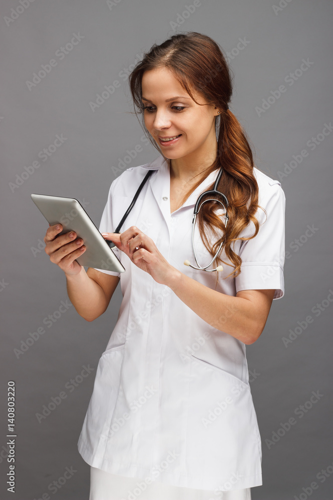 Woman doctor in the white medical uniform with a tablet in the hand Woman doctor in the white medical uniform with a tablet in the hand