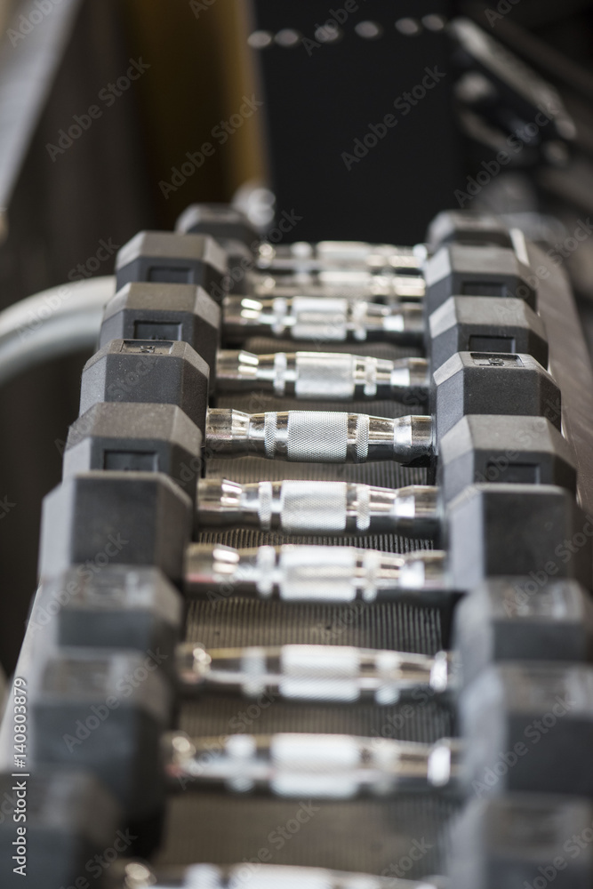 Naklejka premium Closeup of weightlifting dumbbells on a rack in a gym 
