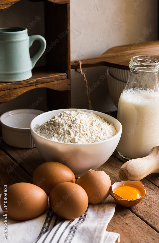 Baking ingredients flour milk eggs rolling pin on wood kitchen table, rustic interior, cozy atmosphere Baking ingredients flour milk eggs rolling pin on wood kitchen table, rustic interior, cozy atmosphere