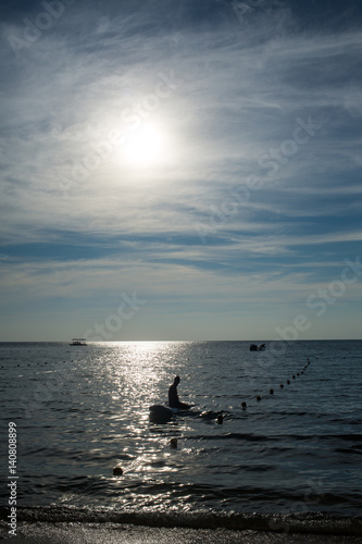Silhouette of surfer man siting on surfboard in sea © eyepark