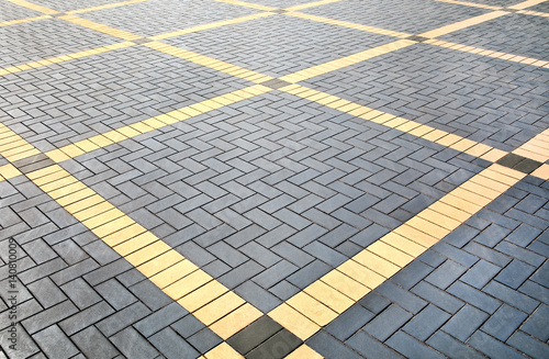 Texture of gray and yellow patterned paving tiles on the ground of street, perspective view. Cement brick squared stone floor background. Concrete paving slab flagstone. Sidewalk pavement pattern.