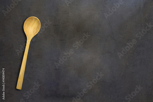Wooden spoon of brown on black wooden plnkwood, high angle top view