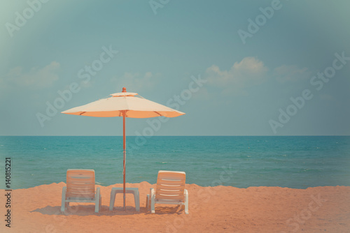 Two beach chairs and white umbrella on the tropical beach at daytime. Vintage tone © nuttawutnuy