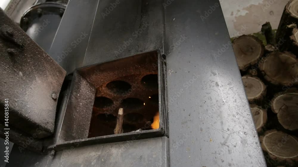 The man opens the door and throws firewood in boiler. Lit the fire.
The man opens the door and throws firewood in boiler. Lit the fire.