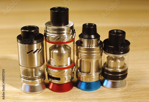 Vaping rebuildable dripping and tank atomizers (RDTA, RTA)on wooden surface close up