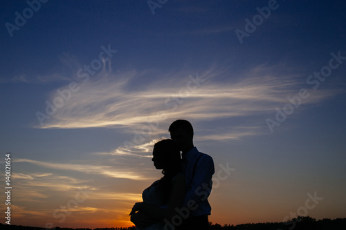 Silhouettes of a loving couple hugging at sunset