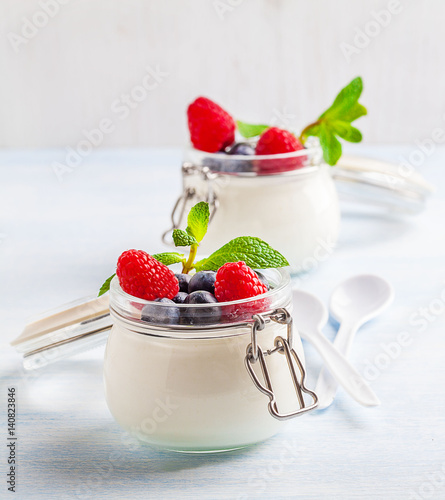 Yoghurt with raspberry  blueberry and mint in glassware on a blue background