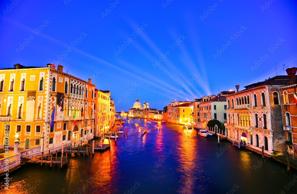 View of the Grand Canal in Venice at night with laser light projected into the sky. 
