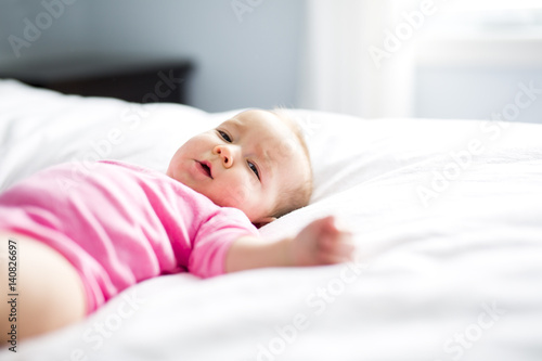 baby girl lying on white sheet