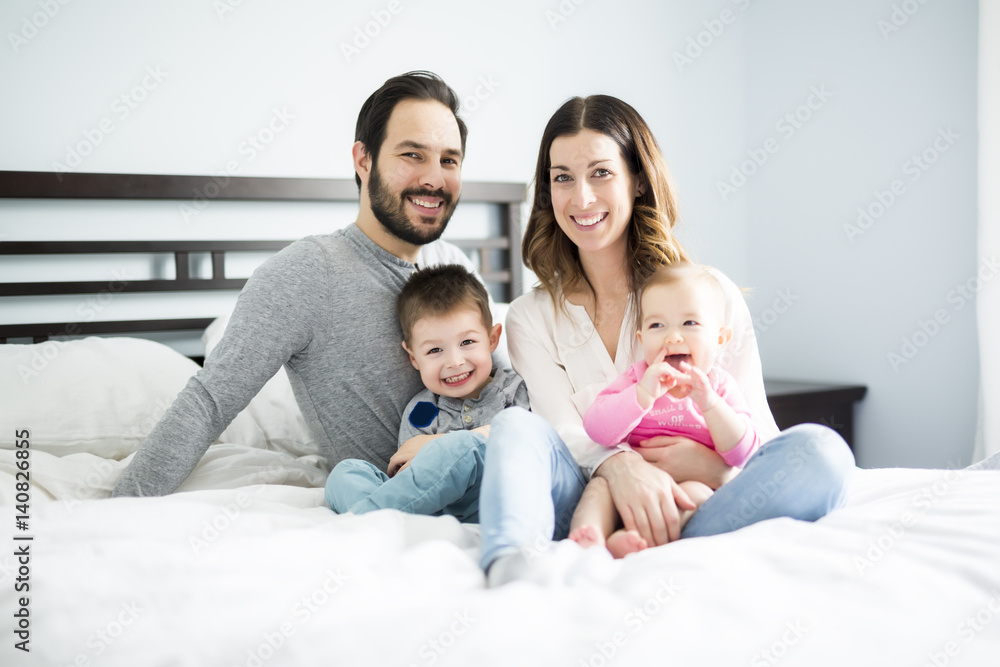four peoples family on a white bed.
