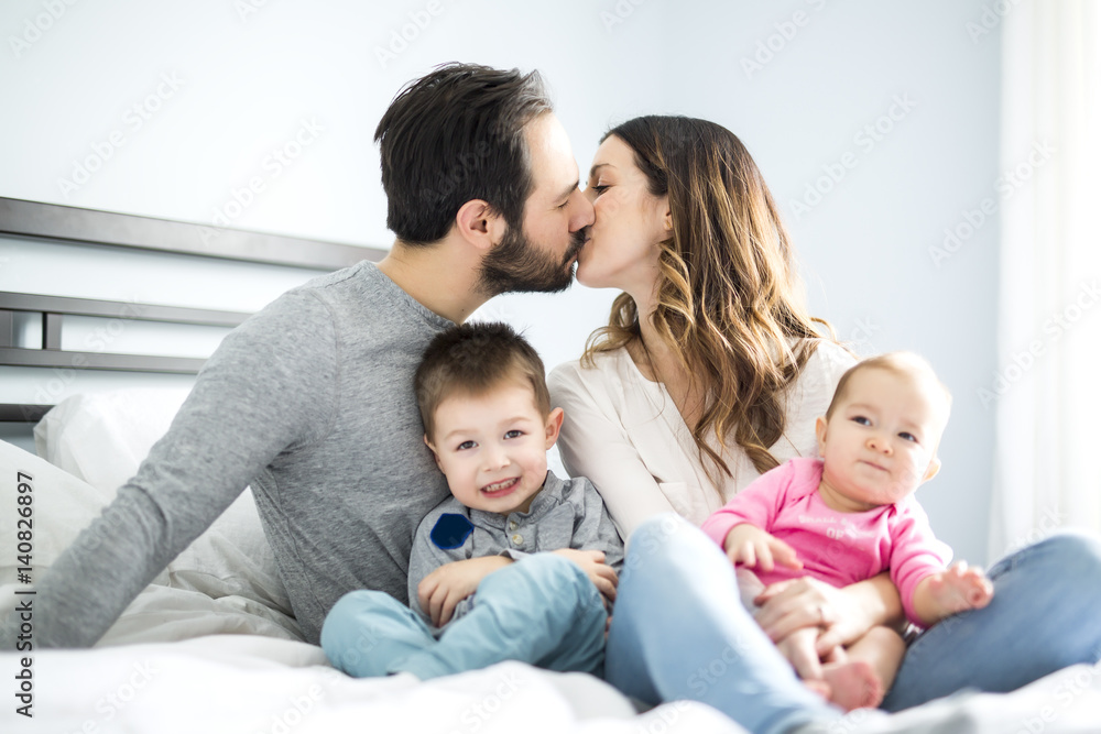 four peoples family on a white bed. four peoples family on a white bed.