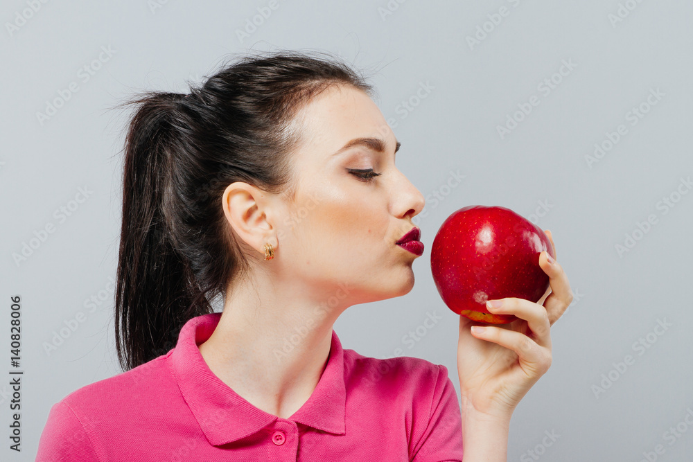 Woman on diet with an apple in the hand against gray background Woman on diet with an apple in the hand against gray background