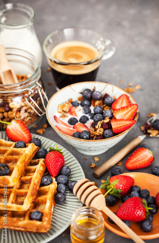 Breakfast table with cereal granola, milk, fresh berries, coffee and waffles Breakfast table with cereal granola, milk, fresh berries, coffee and waffles