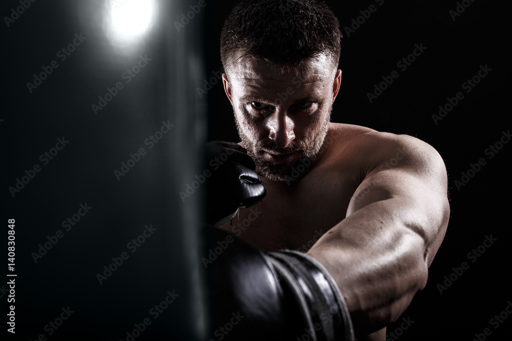 Studio shot of male boxer punching a boxing bag.