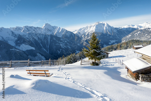 Winterlandschaft mit Schneespur und Almhütten in den Alpen