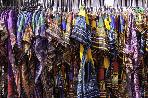A colorful collection of kente cloth dresses at an outdoor festival