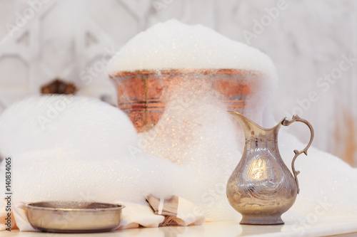Water jar, towel and copper bowl with soap foam in turkish hamam. Traditional interior details photo