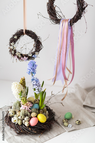 Flower arrangement in a nest with easter eggs on a white table