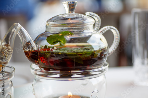 Tea with mint leaves in a glass teapot with a candle.