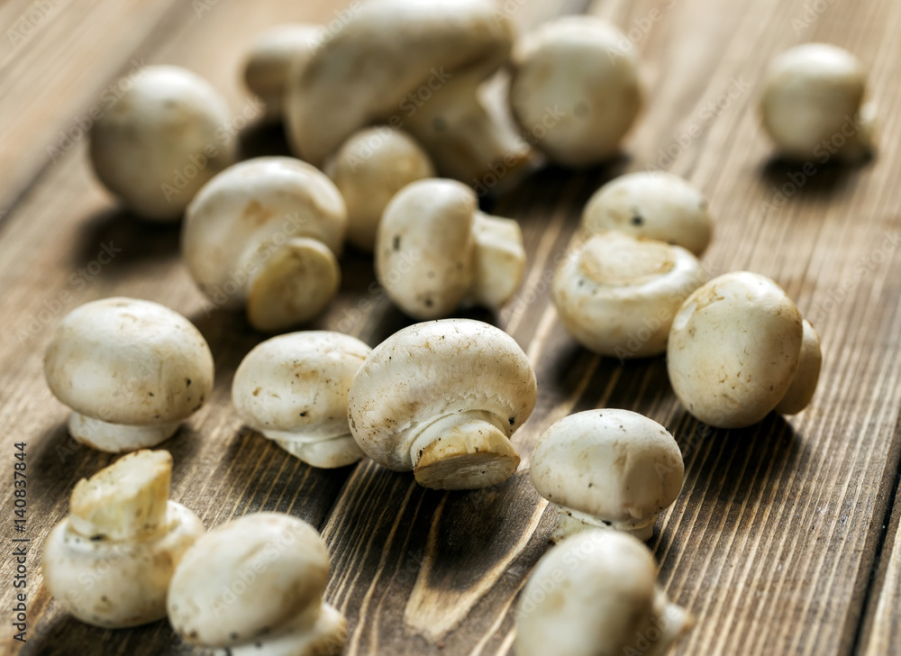 Mushrooms champignons, freshly picked lie on a wooden dark surface