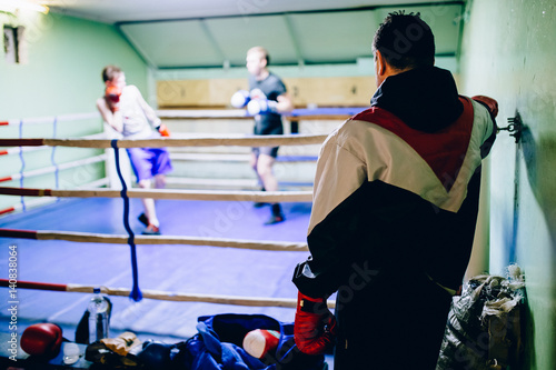 The boxing coach looks at the sparring battles of his athletes wards. Russia.