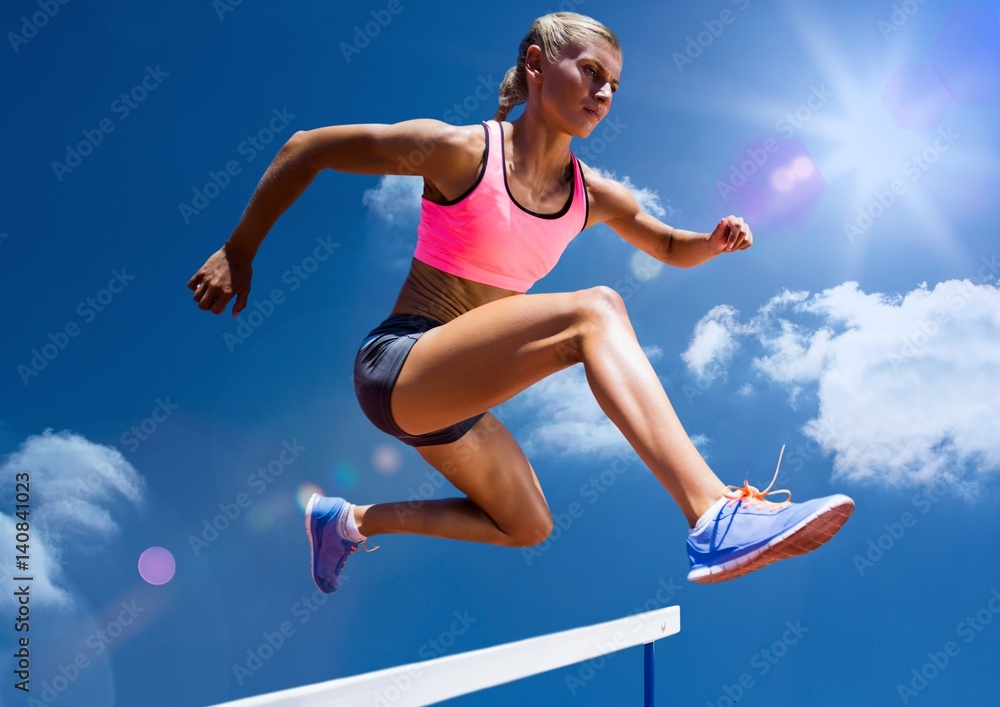 Female athlete jumping above the hurdle