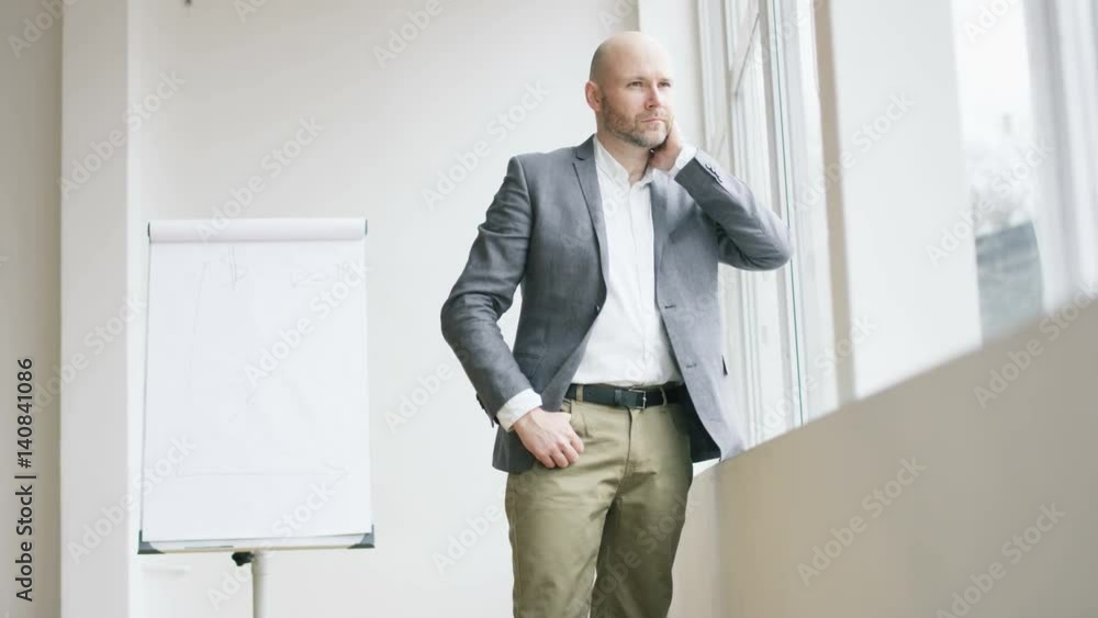 Bald Businessman Supporting His Body with a Sill Bald Businessman Supporting His Body with a Sill