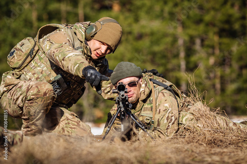 Instructor with operator aiming machine gun at firing range. People and military concept