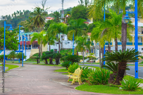 empty footpath with Golden bench in the Park. The green quay road in Samana, Dominican Republic