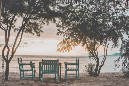 blue table and chairs on beach at sunset
