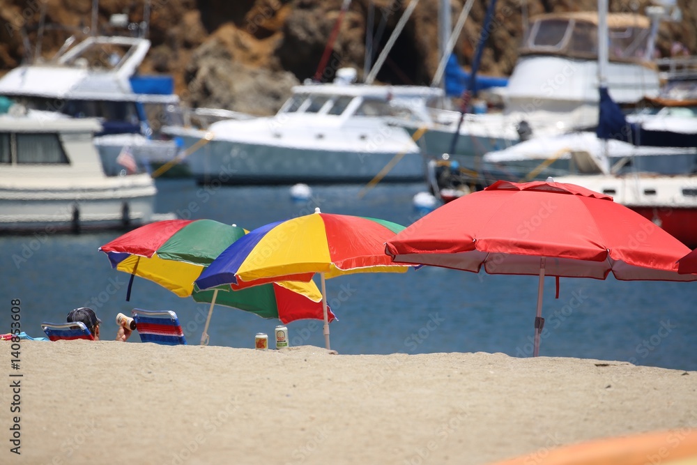 Three Colored Beach Umbrellas With Boats