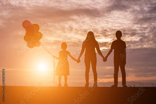 silhouette of woman and child holding colorful of balloons with sunset