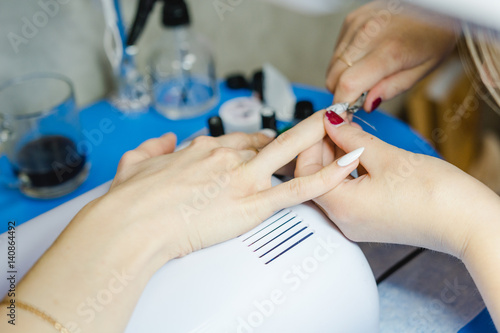 Manicure. The woman cleans and paints nails. The woman processes nails on hands a varnish. Shelak. Gel, a varnish, placing acryle on nails.