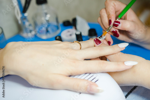Manicure. The woman cleans and paints nails. The woman processes nails on hands a varnish. Shelak. Gel  a varnish  placing acryle on nails.