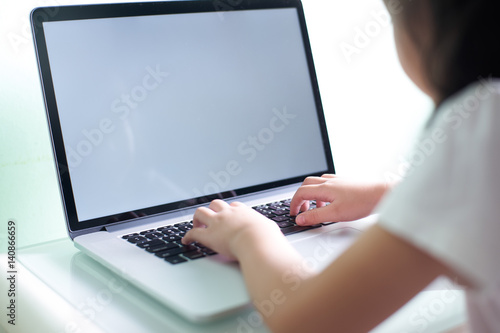 Kid using laptop with white copy space screen .