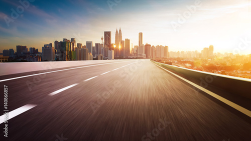 Highway overpass motion blur with city skyline background . Sunset scene .