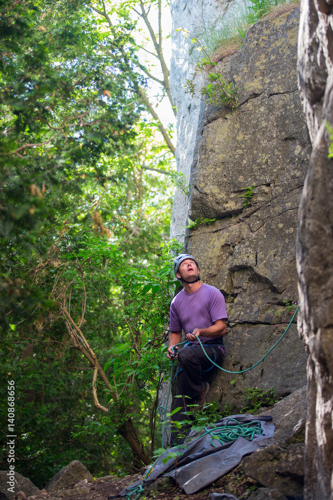 Man belays his friend while rock climbing