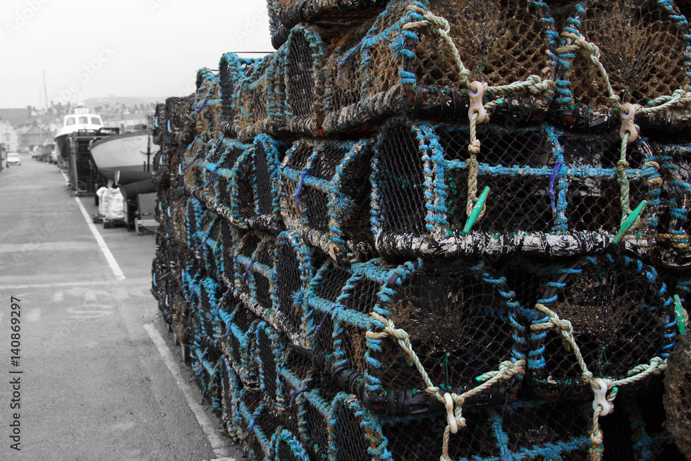Lobster crab pots stacked on a quayside edited using selective colour