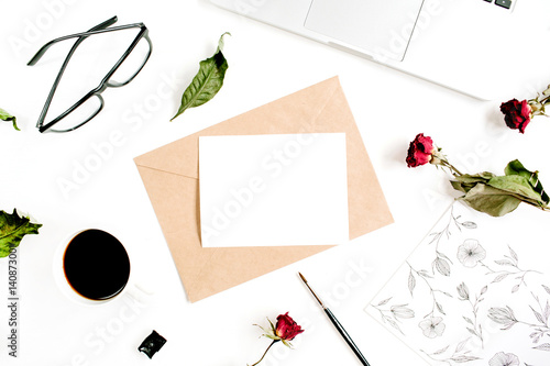 Paper blank, craft envelope, red roses, laptop, coffee on white background. Flat lay, top view