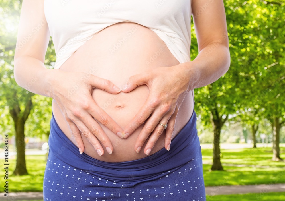 Pregnant woman forming heart shape with hands on her stomach Pregnant woman forming heart shape with hands on her stomach
