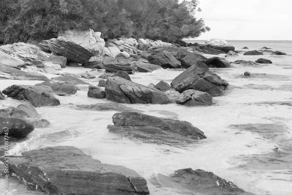 Large stones in the sand of the sea beach - black and white